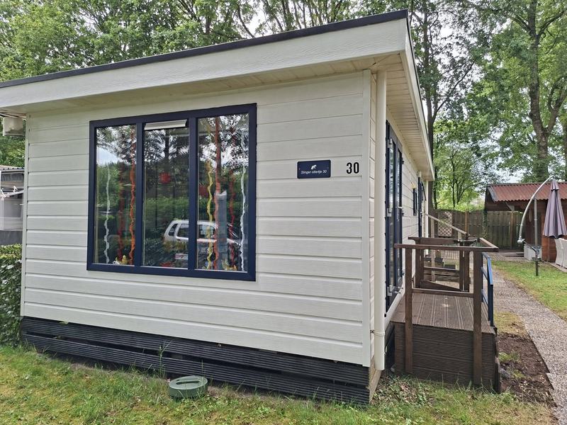 Het witte chalet met blauwe kozijnen en huisnummer 30
